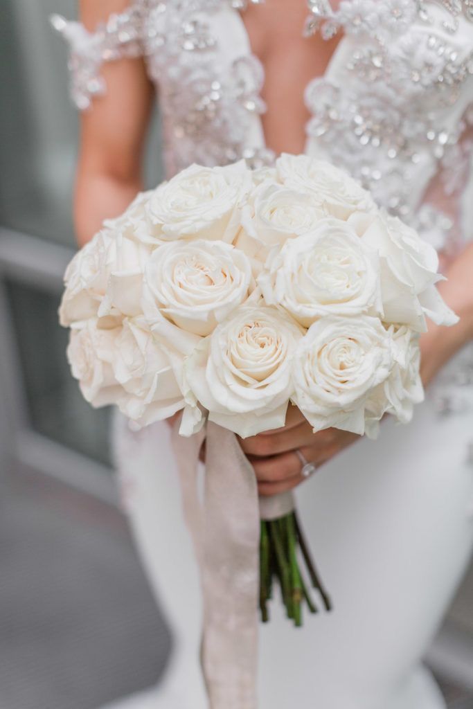 a bride holding a bouquet of white roses