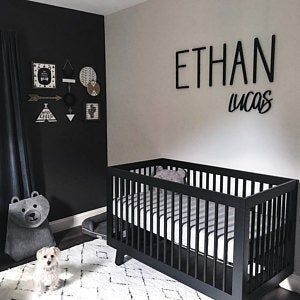 a black and white baby's room with a crib, teddy bear and wall hangings