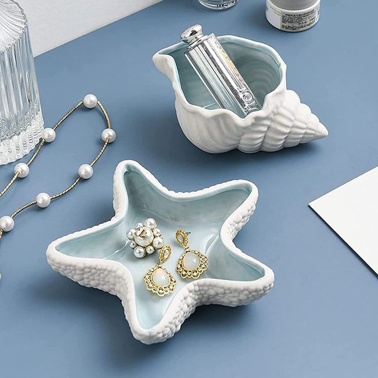 two star shaped dishes on a blue table with pearls and other items around them,