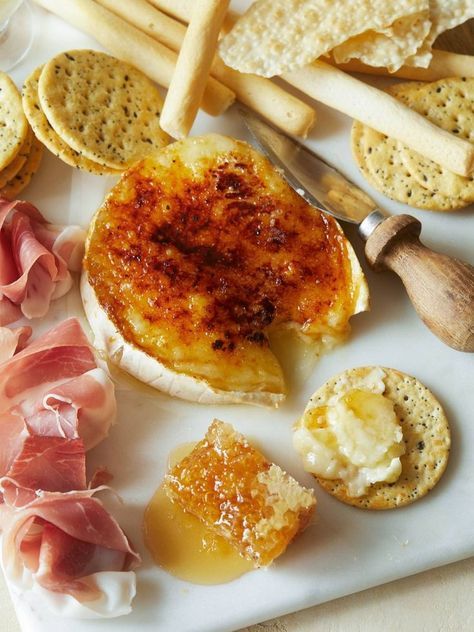 an assortment of cheeses, crackers and meats on a white plate with utensils