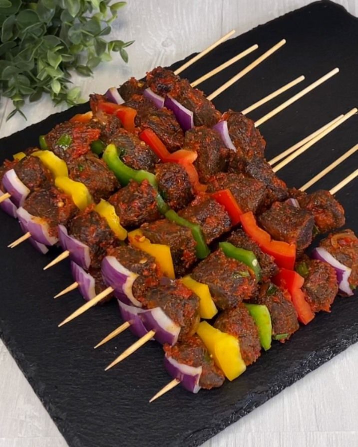 skewered meat and vegetables on a black plate