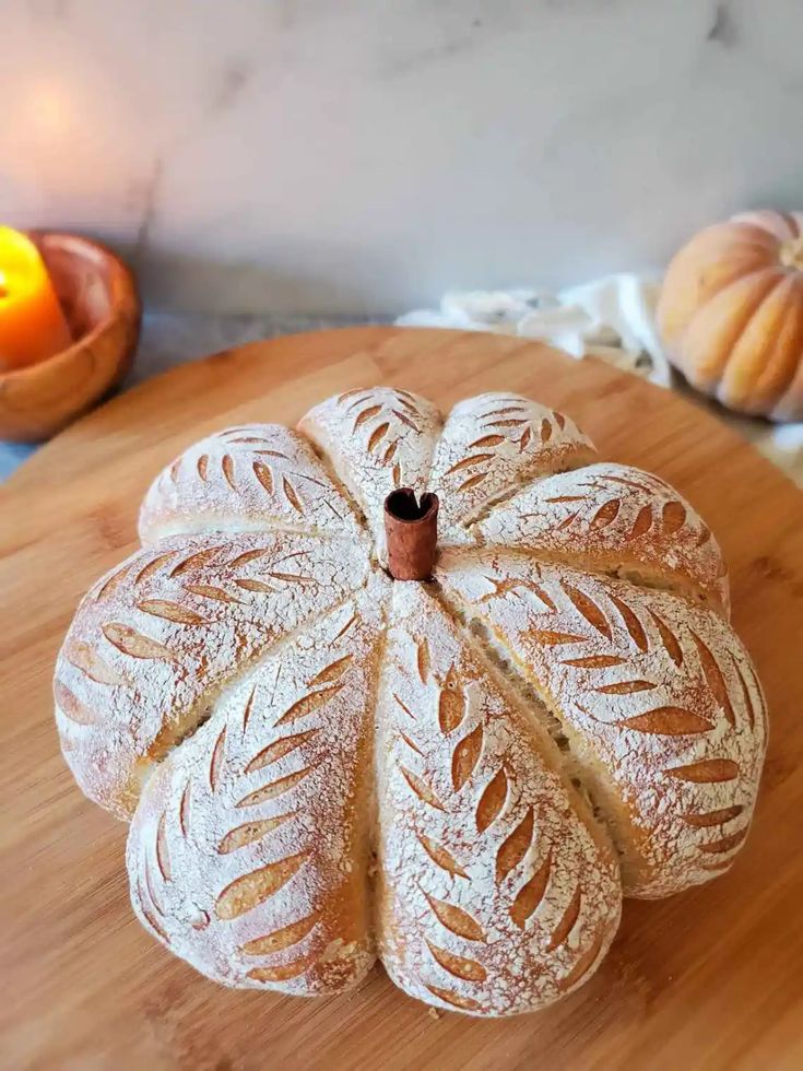 a loaf of bread sitting on top of a wooden table next to two pumpkins