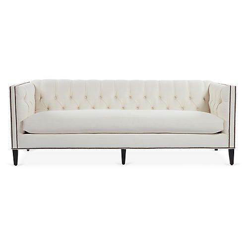 a white couch with black legs and buttons