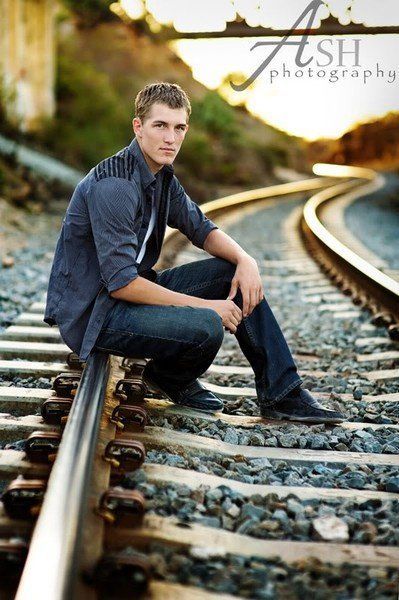 a man sitting on train tracks with his hands in his pockets and looking at the camera