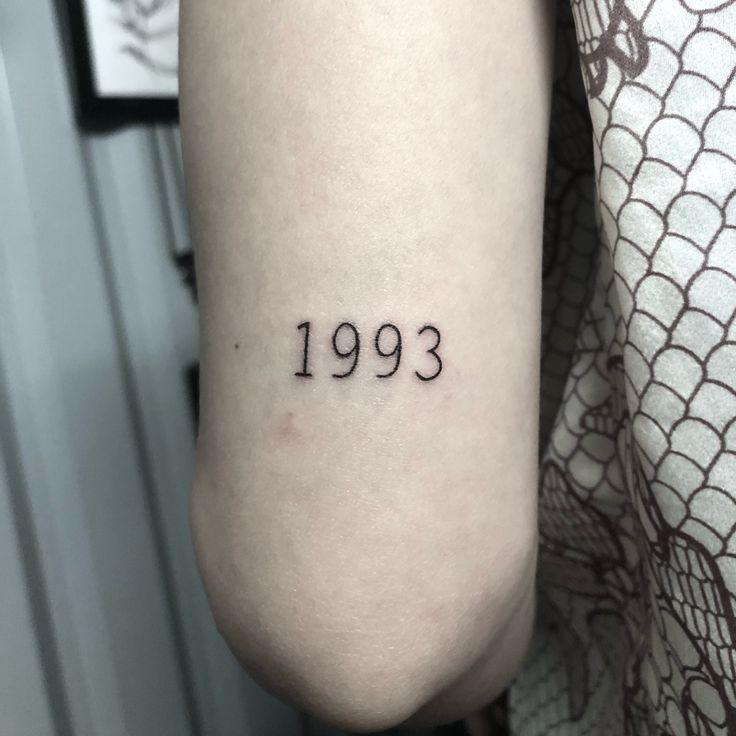 a person with a tattoo on their arm that reads, 1933 in black ink and the number thirteen