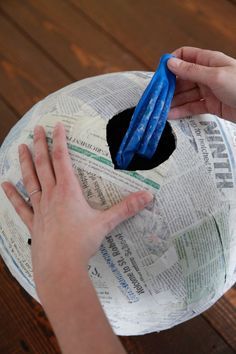 a person holding a piece of paper with their hand on top of an object that looks like a toilet paper roll