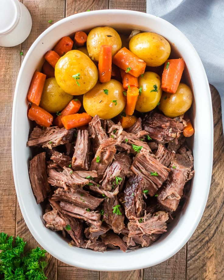 a bowl filled with meat and vegetables on top of a wooden table