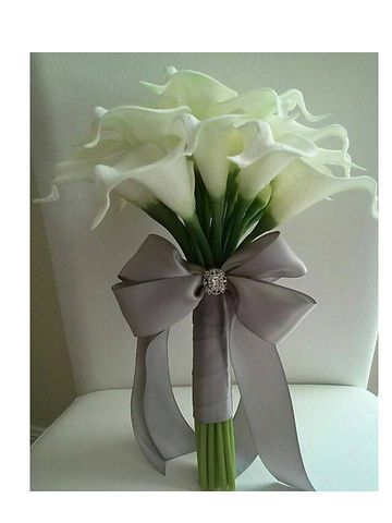 a bouquet of white flowers in a vase with a bow on the back of it