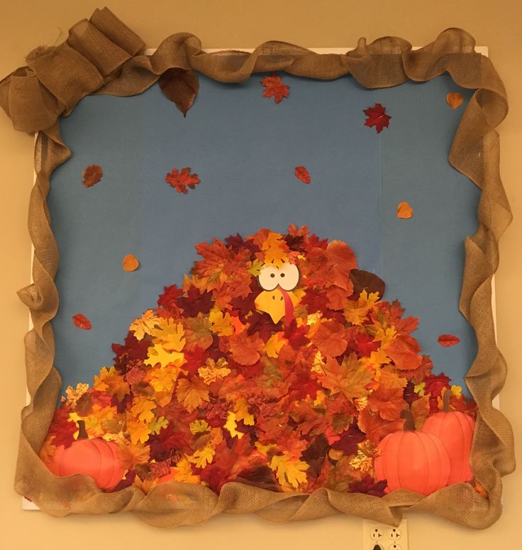 an art project with pumpkins and leaves in the shape of a scarecrow sitting on top of a pile of fall leaves