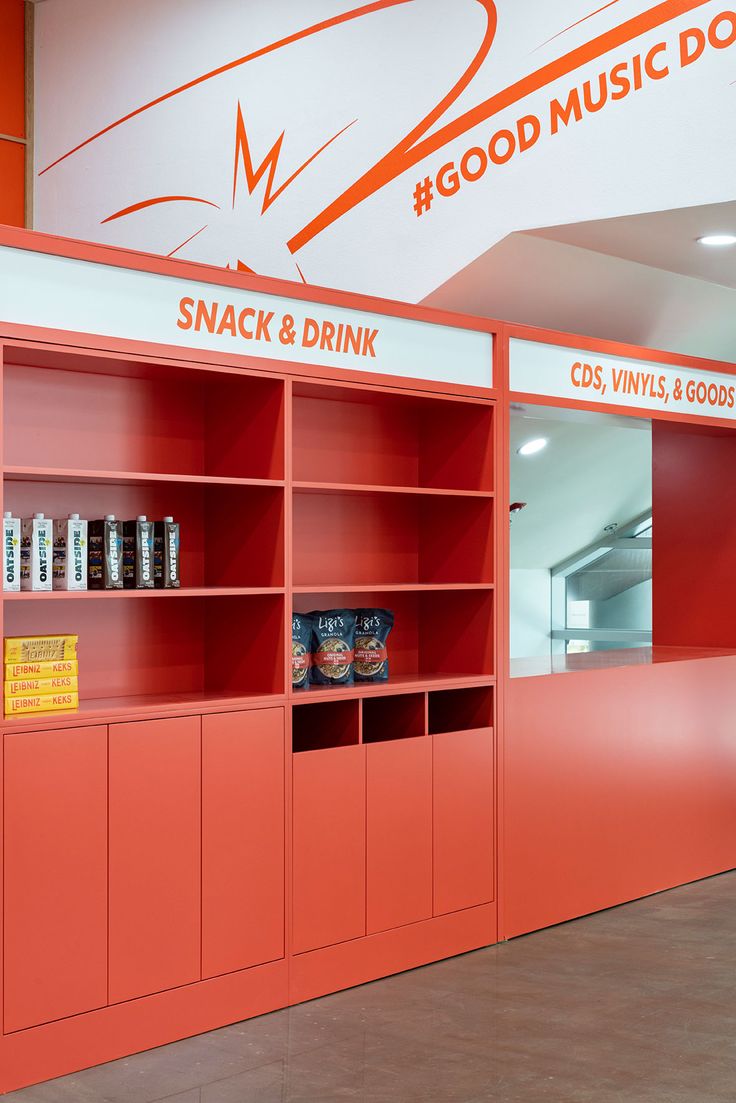 an orange book case with snacks and drinks on it's shelves in front of a sign that reads good music donuts