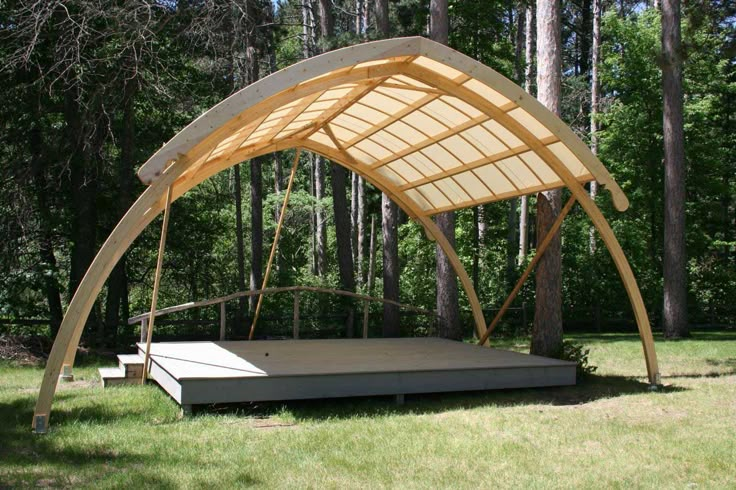 a wooden structure in the middle of some grass