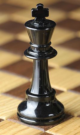 a black and silver chess piece sitting on top of a wooden floor