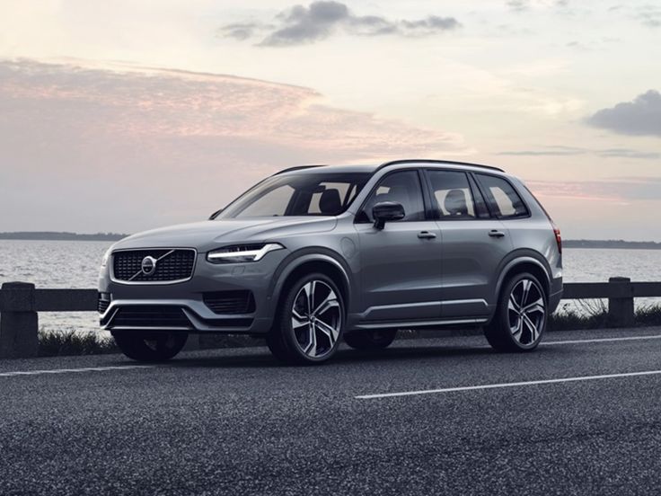 a silver volvo suv driving down a road next to the ocean