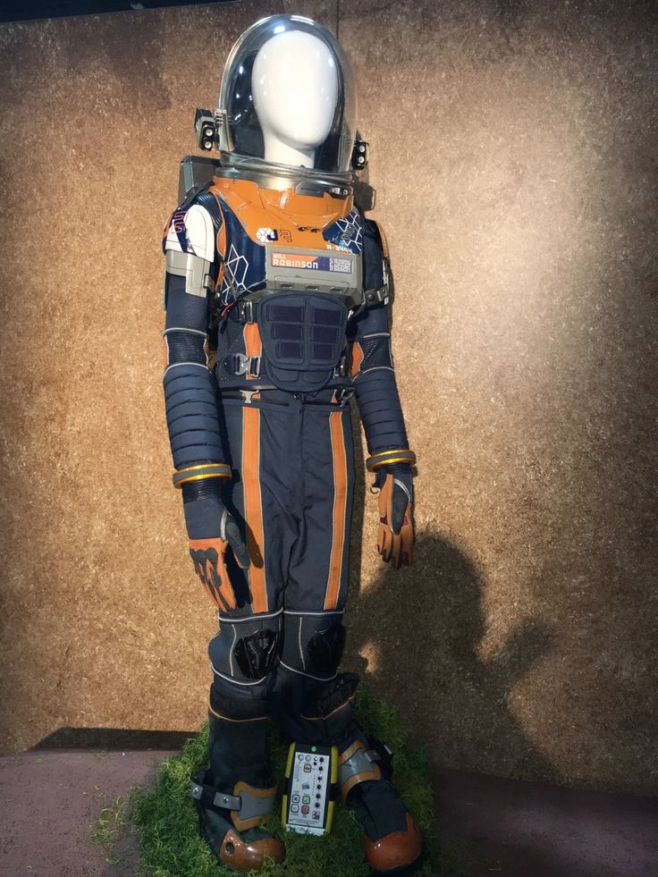 an astronaut's space suit on display in a museum case with grass and dirt