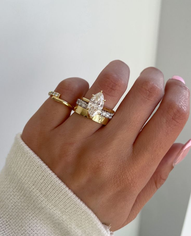 a woman's hand with two gold rings on it and one diamond ring in the middle