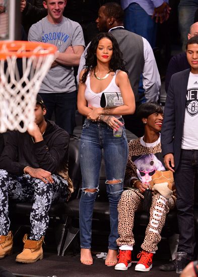 a woman standing on top of a basketball court next to people sitting in the bleachers