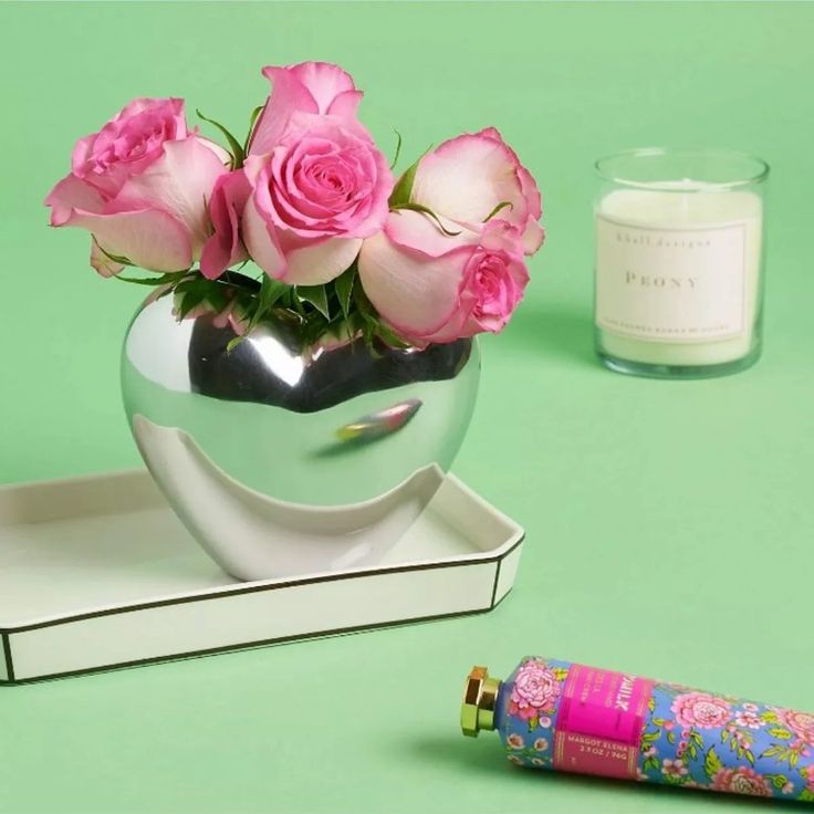 there is a vase with pink roses in it and a pen on the table next to it