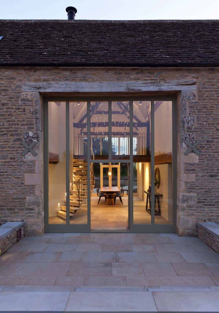 an open glass door leading into a room with brick walls and stone steps in front of it