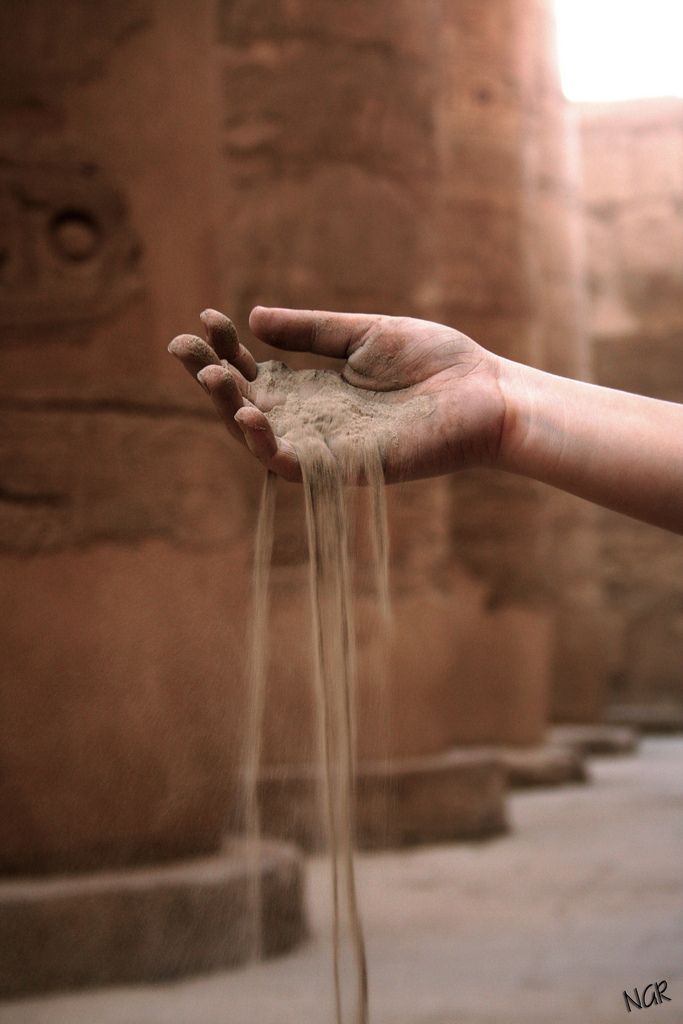 a person's hand is spewing sand from their palm to the ground