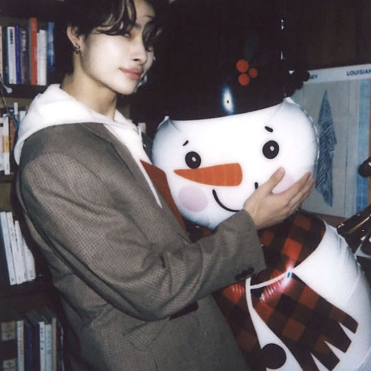 a woman holding a snowman in front of a bookshelf