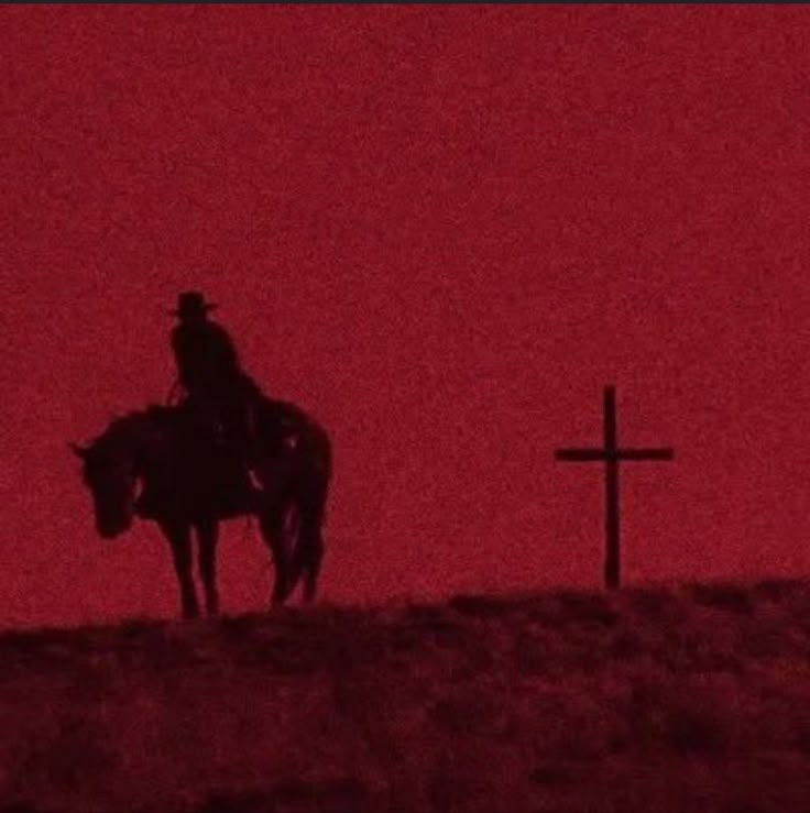 a man riding on the back of a horse next to a cross