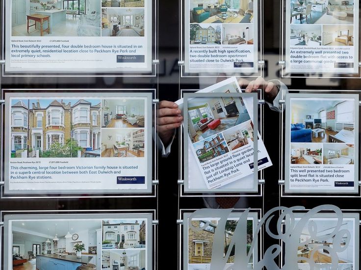 a person holding up a newspaper in front of a display case with pictures on it