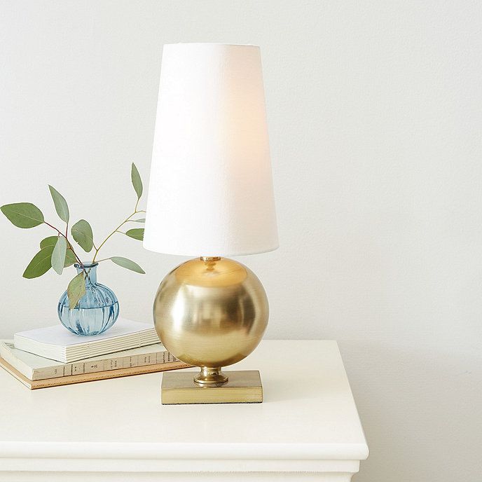 a lamp sitting on top of a white table next to a book and a plant