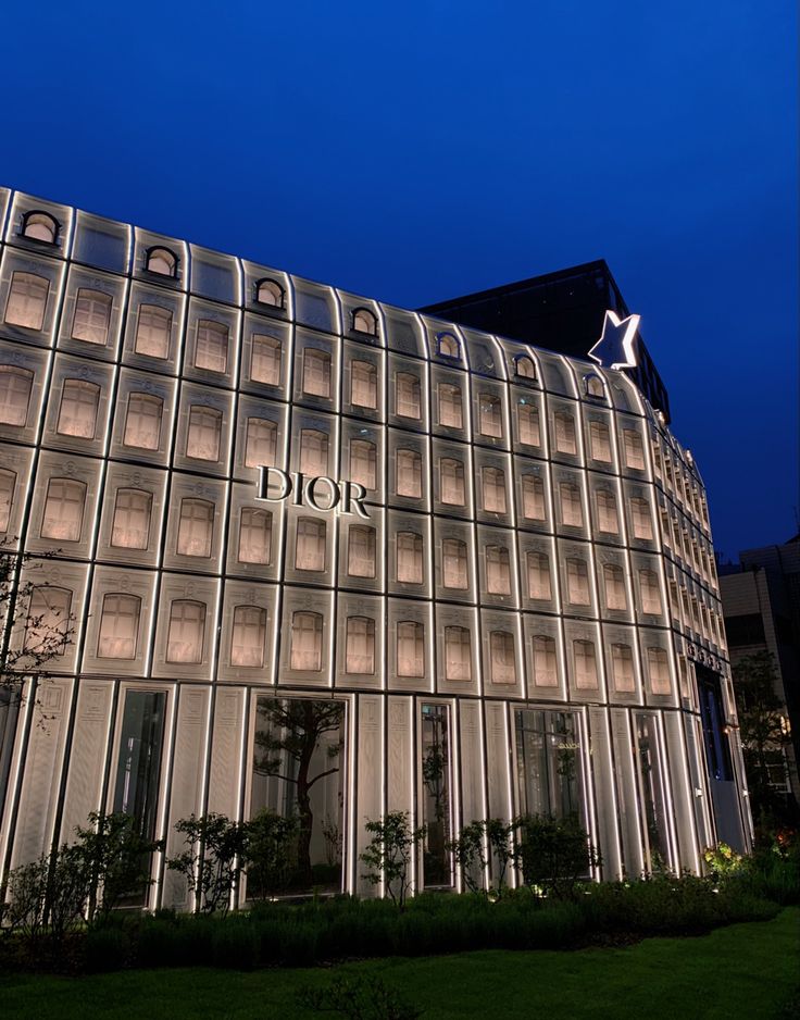 the exterior of a modern building lit up at night with lights shining on it's windows