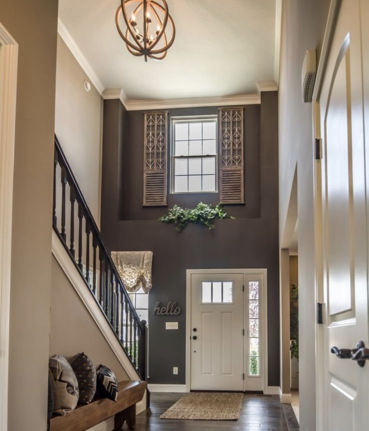 an entryway with stairs, windows and a bench in front of the entrance door