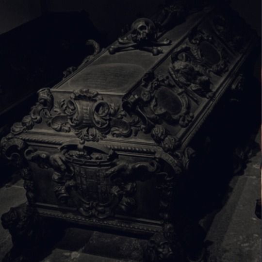 an ornately carved wooden bench in a dark room with other items on the floor