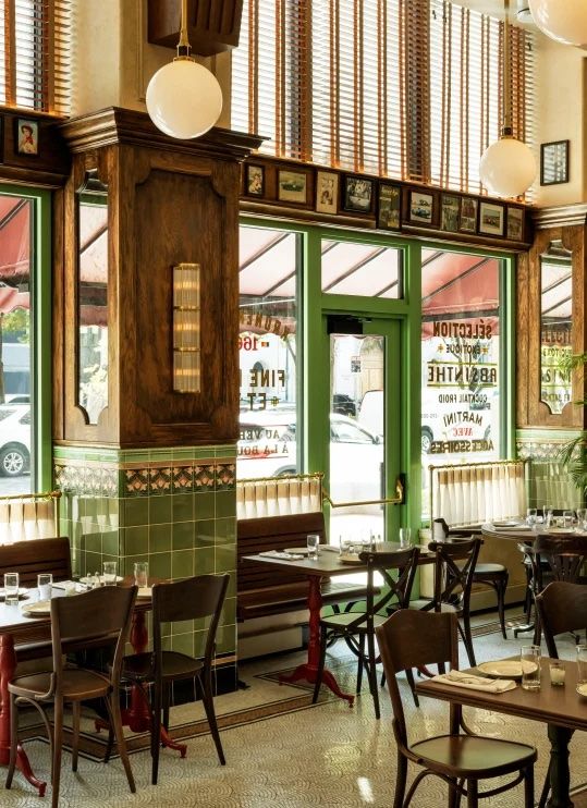 the inside of a restaurant with tables, chairs and green doors that have windows on them