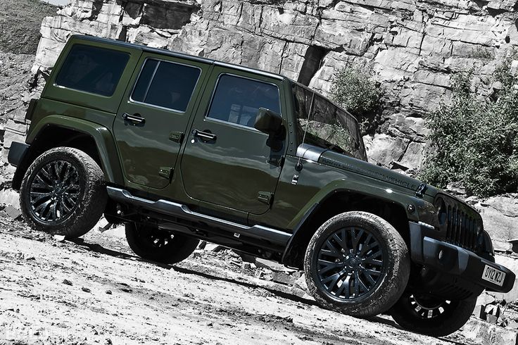 a green jeep parked in front of a rock wall