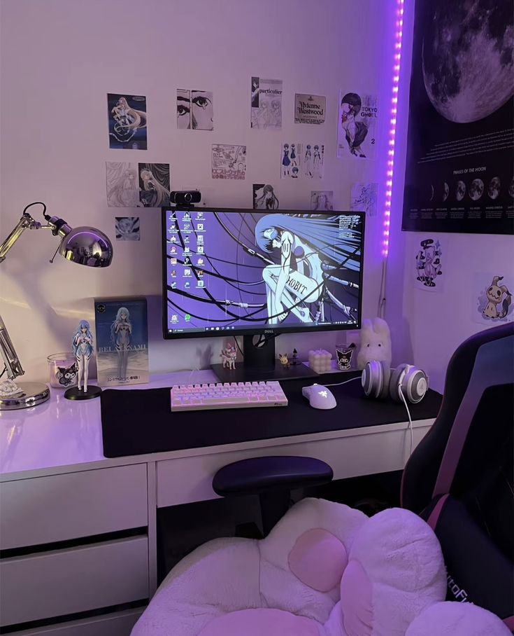 a desk with a computer monitor and headphones on it, in front of a purple light