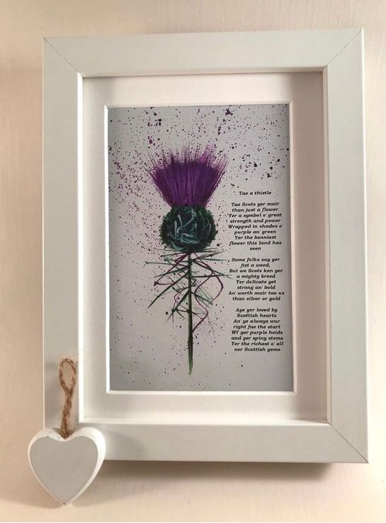 a white frame with a purple flower in it and a small heart on the wall