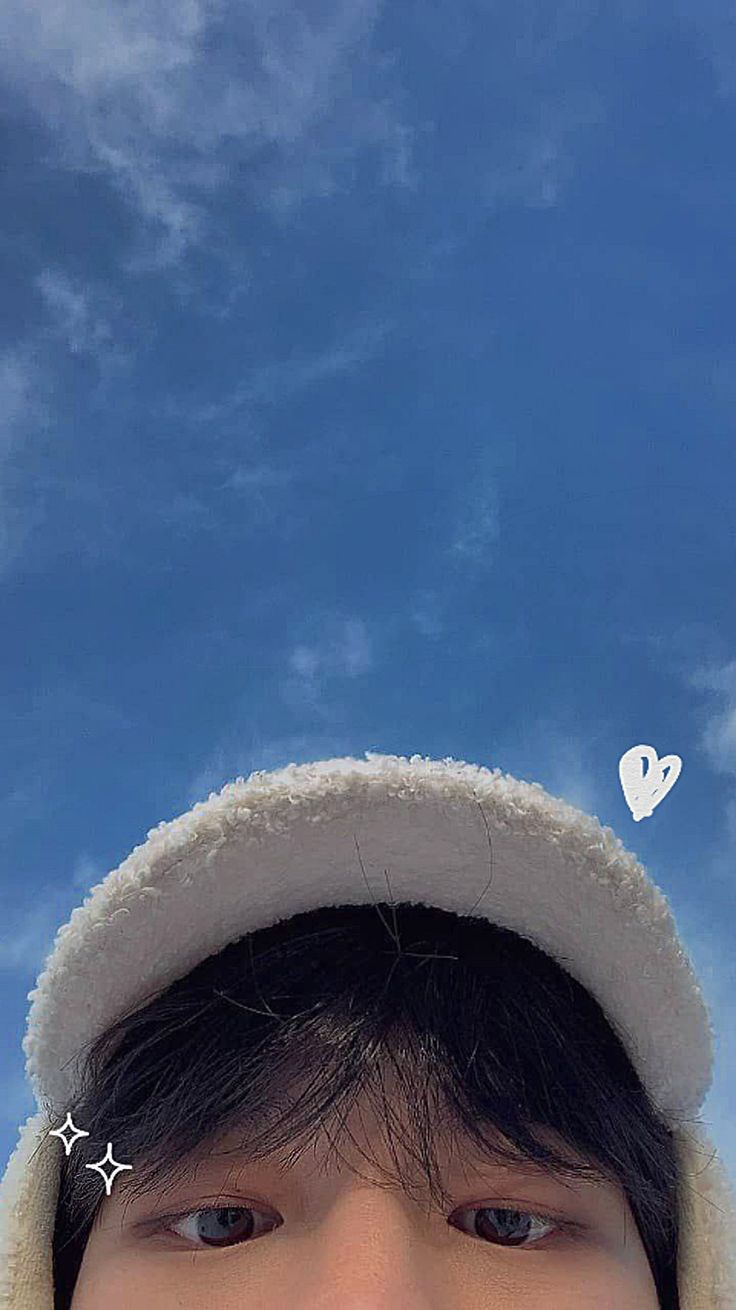 a young man wearing a white hat with hearts on his ears and nose, looking up at the sky