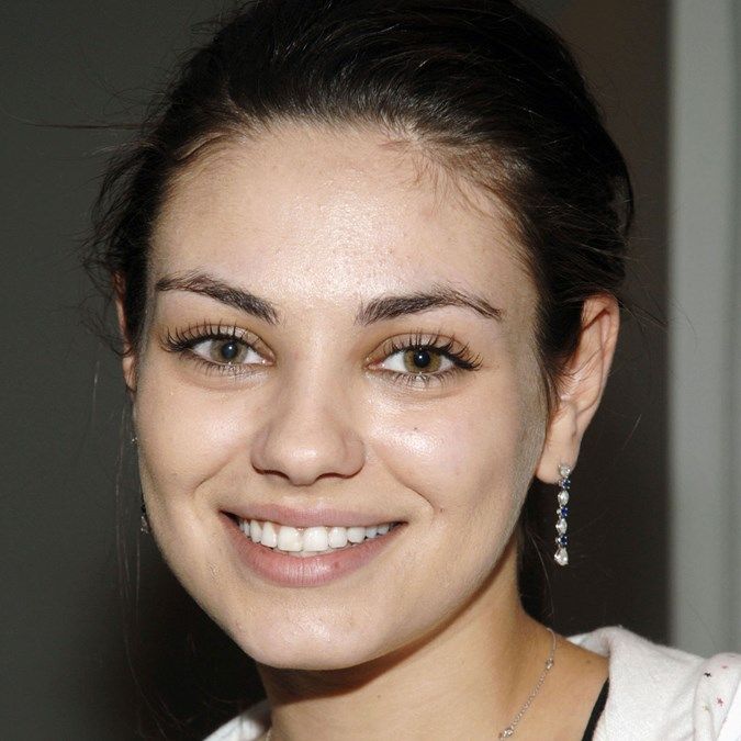 a close up of a person with a smile on their face and wearing earrings in her hair