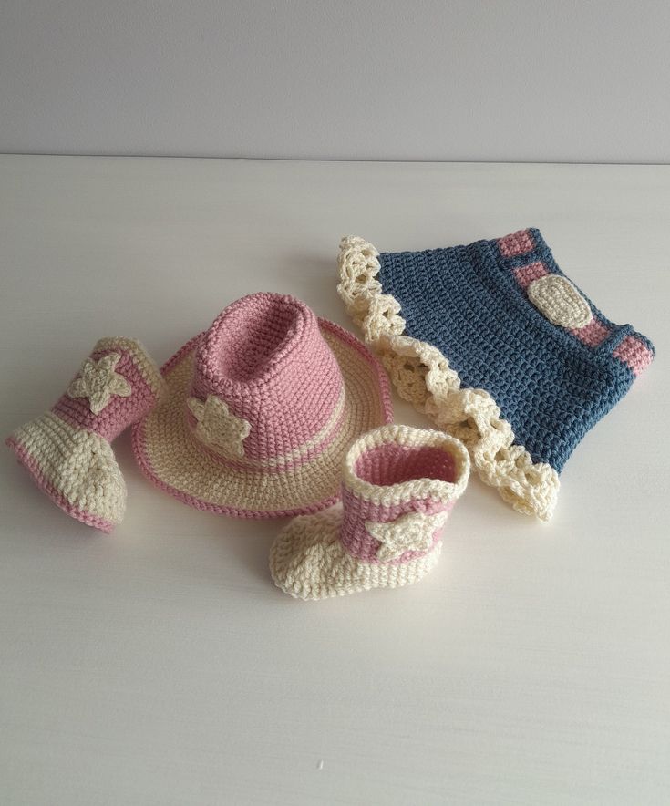 a crocheted hat, booties and diaper sit on a table