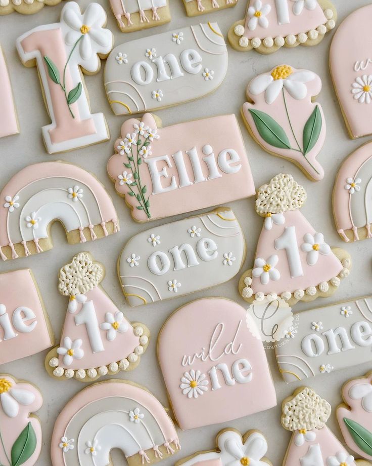 decorated cookies with the number one and two for first birthdays are displayed on a table