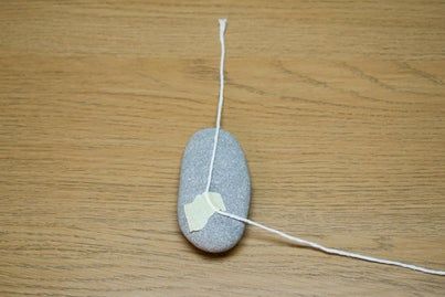 a rock with a piece of string attached to it on a wooden surface, sitting on top of a table