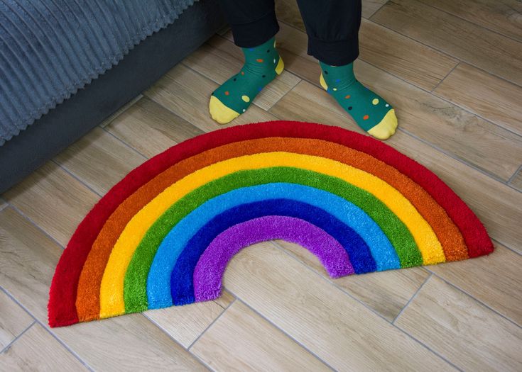 a rainbow rug is on the floor next to a person's feet