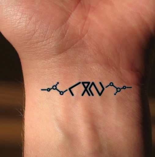 a small tattoo on the wrist of a person's left hand, which is connected to two wires