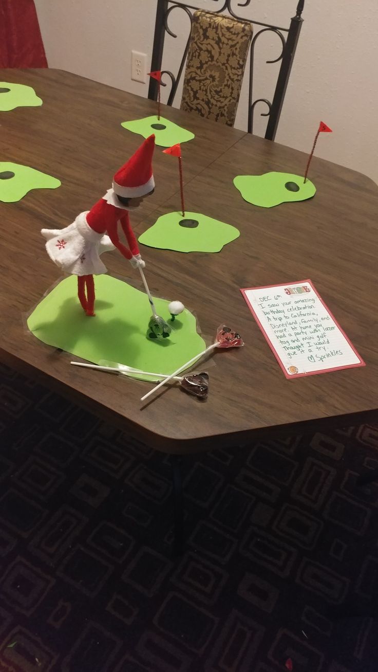 the elf is playing with his golf club on the dining room table, which has been made out of paper