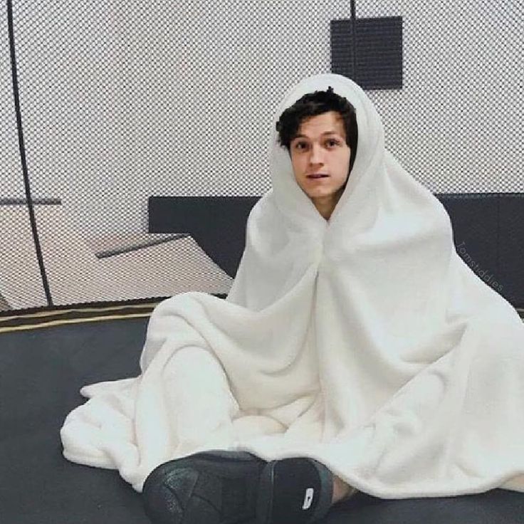 a person sitting on the ground wrapped in a blanket