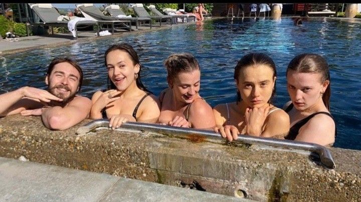 five people in a swimming pool posing for the camera