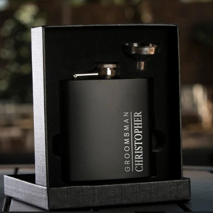 a black and silver flask in a box with the initials m w t on it