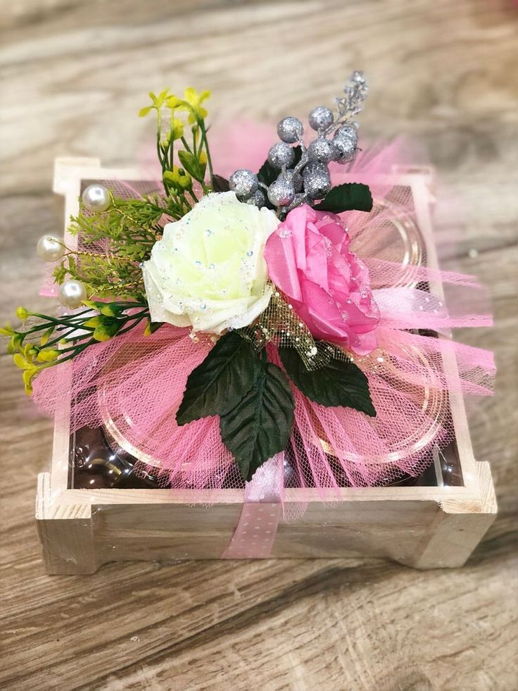 a pink and white flower arrangement in a wooden box