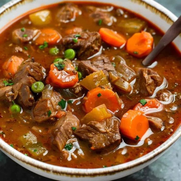 a bowl of beef stew with carrots, celery and green onions in it