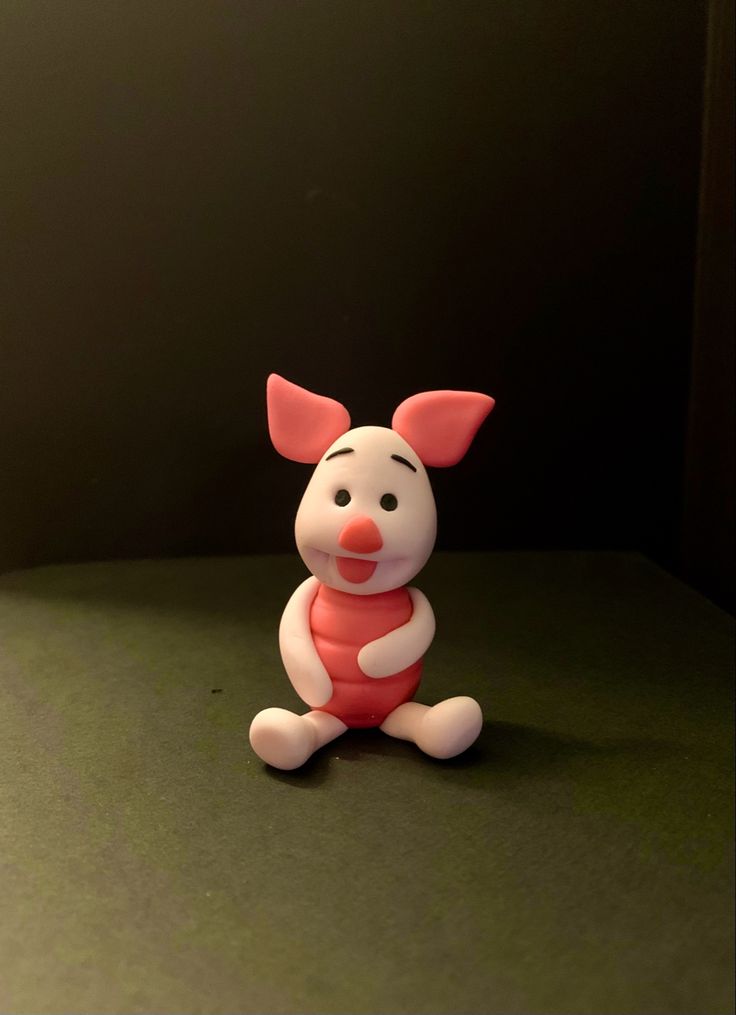 a small plastic toy sitting on top of a green table next to a black wall