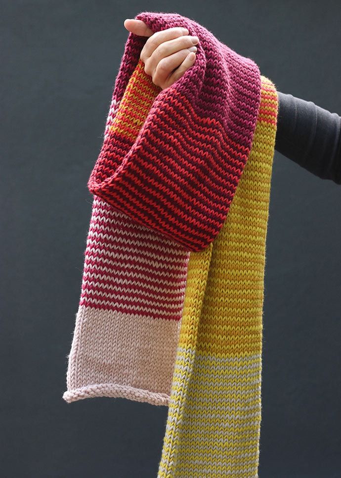 a person holding up a knitted scarf