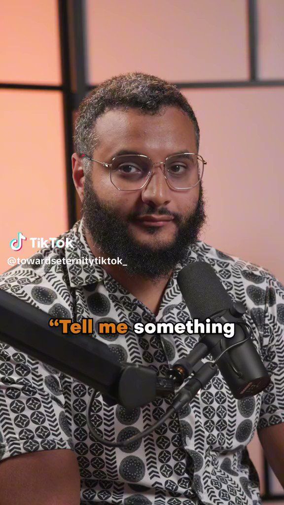 a man with glasses and a beard is holding a microphone in front of his face